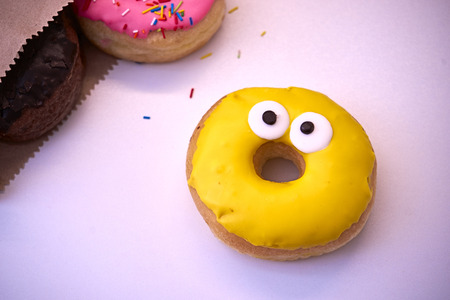 Delicious donuts fall out of the package on a wooden backgroundの写真素材