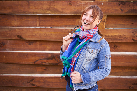A beautiful girl stands on the background of a wooden wallの写真素材