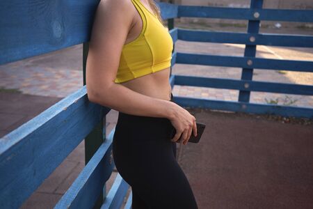 Athletic woman stands on the sports ground with a mobile phone.の写真素材
