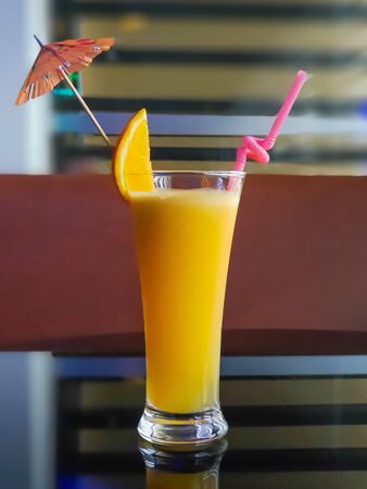 Orange juice with a straw and sliced orange on topの写真素材