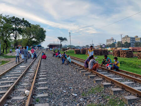 Dhaka, Bangladesh - 11.07.2021: Helpless poor people sitting on a railway during corona lock down in bangladesh with no work. Crisis during the corona Shutdown in bangladesh.のeditorial素材
