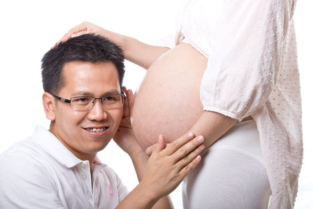Lovely pregnant with her husband used hand  touched torso for feeling love their baby in studioの写真素材