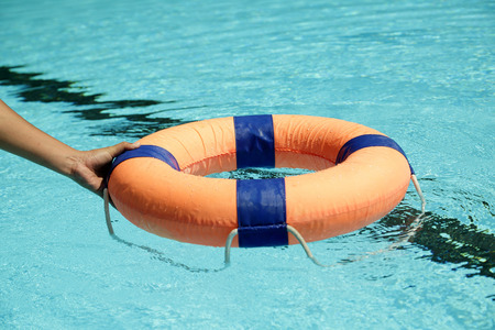 Peolple throw Life ring floating to someone in the poolの写真素材