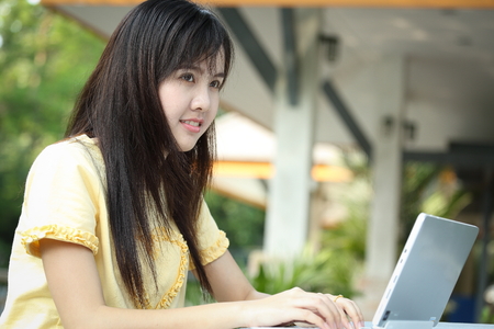 Asian young girl use laptop for search information in the gardenの写真素材