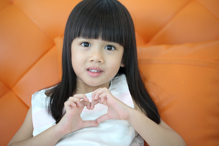 lovely girl use hand cover and touch to make heart sign  in studioの写真素材