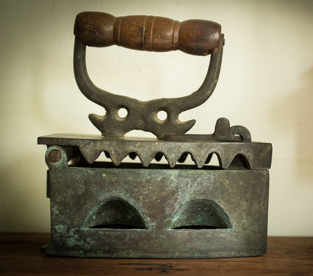 Close up Antique iron lay down on the wood table.の写真素材