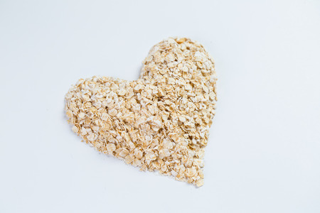 Macro Oat flakes pile heart  on the white backgroundの写真素材