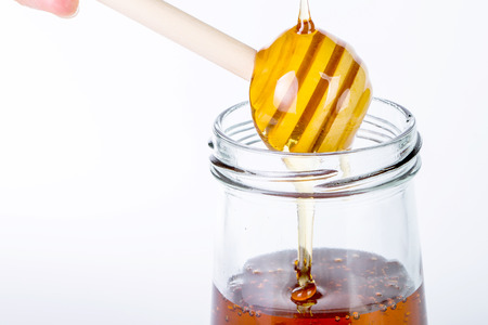 Honey diping and dipper isolated with white backgroundの写真素材