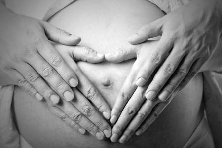 Lovely pregnant with her husband used hand  touched torso for feeling love their baby in studioの写真素材
