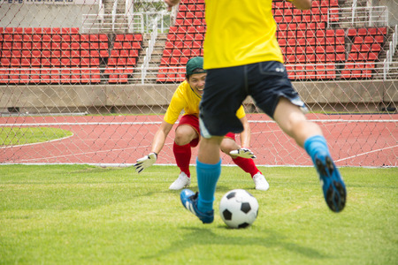 Attack soccer player shooting to defense team in football stadium.の写真素材
