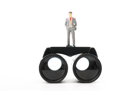 Businessman doll stand on top of binocularsの写真素材