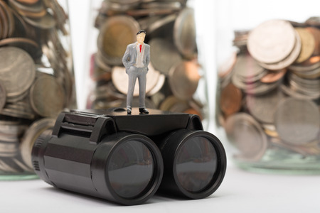 Black Binoculars with human figure isolated on coin jars backgroundの写真素材