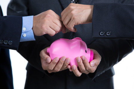Businessman used hands for insert coin to piggy bank for deposit their investment in the futureの写真素材