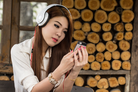 Young woaman enjoying  music with smart phone in coffee shopの写真素材