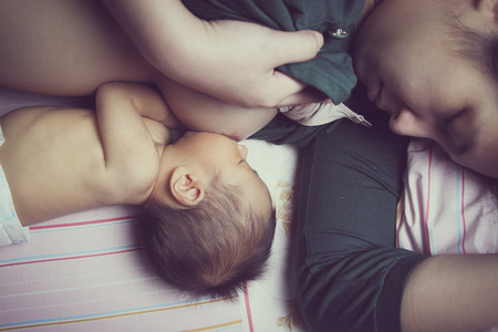 Mother Breastfeeding her baby on the bed.の写真素材