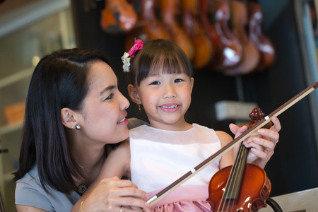 Mam and daughter portrait with violin in studio school.の写真素材