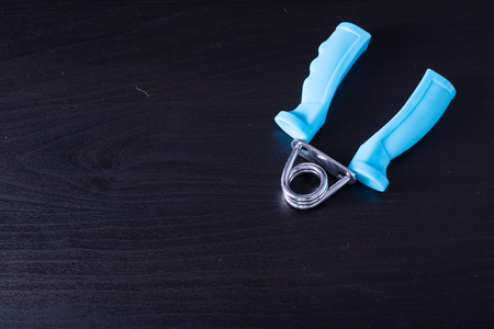 Blue Hand Gripper on black wood board.