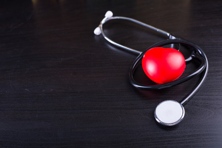 Black stethoscope heart on black wood board.の写真素材