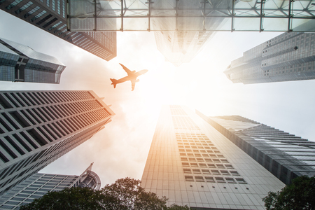 Airplane flight over city building for transportation passengersの写真素材