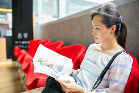 Asian woman reading magazine in coffee shop.の写真素材