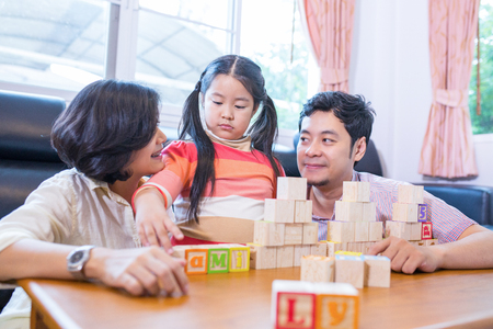 Asian family play cube wood for build words together in guest room.の写真素材