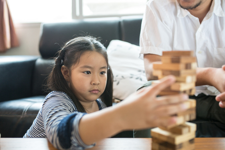 Happy Asian family having fun playing Jenga in the living roomの写真素材