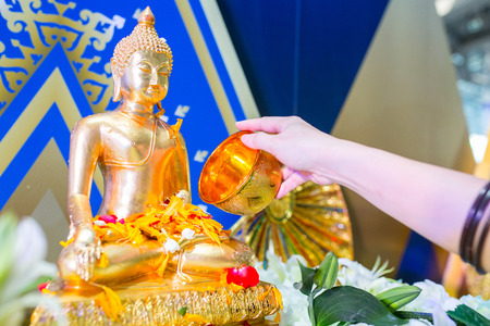 Songkarn festival using fresh and clean water with flower to clean buddha statue in Thailand.の写真素材