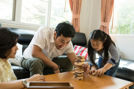 Happy Asian family having fun playing Jenga in the living roomの写真素材