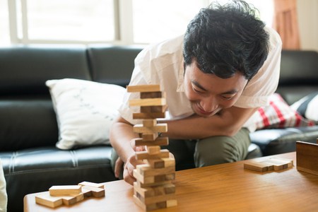Happy Asian family having fun playing Jenga in the living roomの写真素材