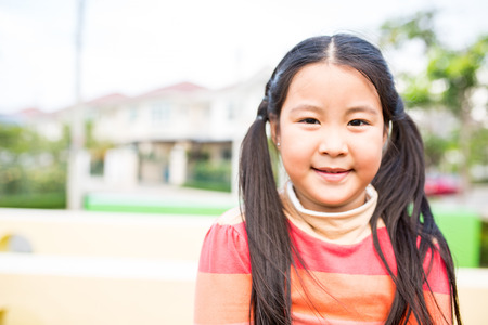 Asian children smile in the garden outside.