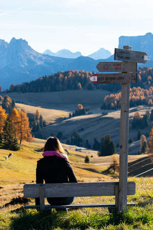 Asian woman sitting wooden bench with sign road name.の写真素材