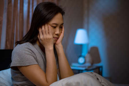 Depressed Asian woman can not sleep on the bed.Insomnia syndrome sleepless after unhappy and worry her lifestyle.Adult feel sadness.Bad emotion.の写真素材