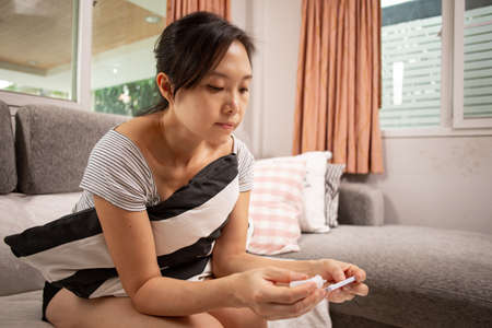 Asian woman using rapid test kit for check coronavirus and wait for check result .Analyze virus desease with test kit.の写真素材