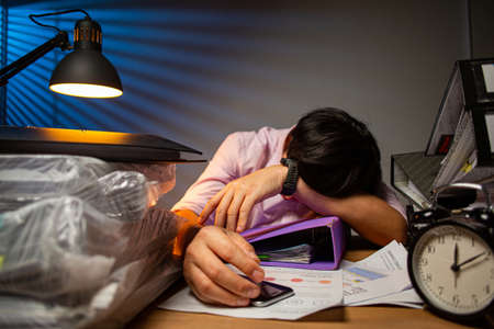 Thai office man sleepy staff sleep on the desk after finished report at night.Businessman in workplace for do project deadline.Asian adult lying for relax with his report.の写真素材