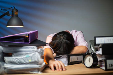 Thai office man sleepy staff sleep on the desk after finished report at night.Businessman in workplace for do project deadline.Asian adult lying for relax with his report.の写真素材