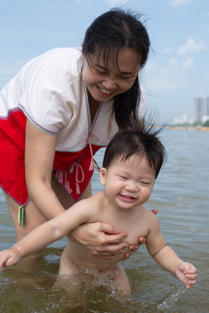 Asian mother and baby boy play beach  together in holiday.の写真素材