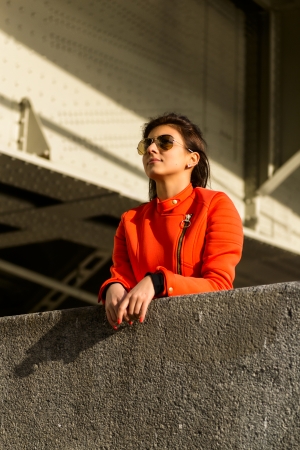 Young nice girl in vibrant orange jacket walking in autumn city の写真素材
