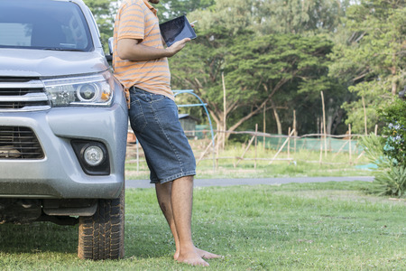 Man standing barefoot on the grass beside the car.