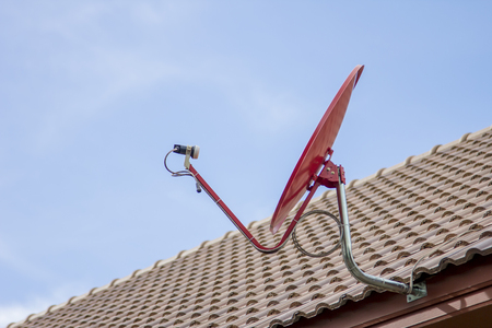 Red satellite dish on the roofの写真素材