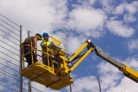 Hydraulic mobile construction platform elevated towards a blue sky with construction workers
