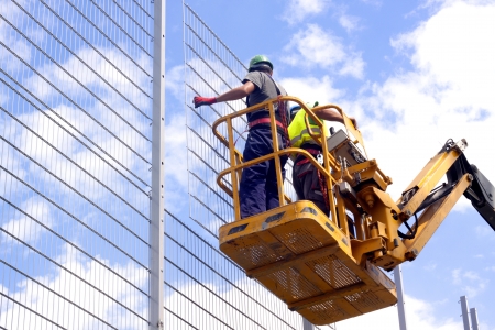 Hydraulic mobile construction platform elevated towards a blue sky with construction workersの写真素材