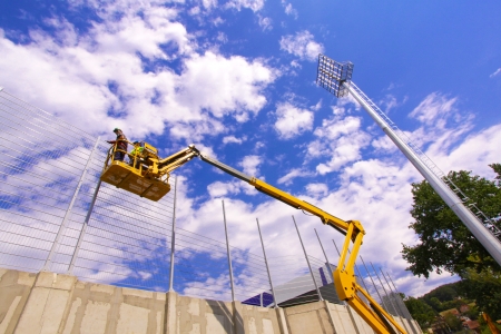Hydraulic mobile construction platform elevated towards a blue sky with construction workersの写真素材