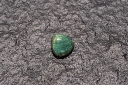 Prasiolite (green quartz) isolated on black stone background. Macro shot