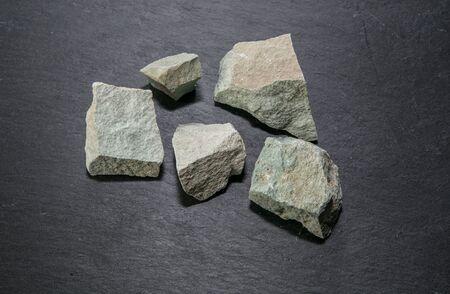 Zeolite mesolite raw stones on black stone  background.Macro shot