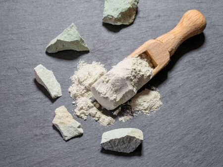 Zeolite natural raw stones and zeolite powder on black stone  background.Macro shotの写真素材