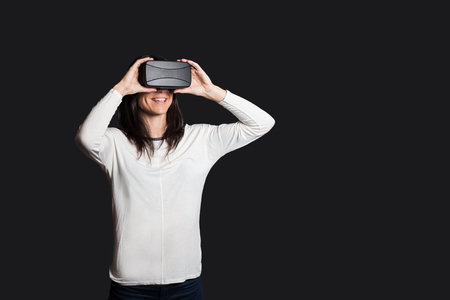 casual young woman using virtual reality glasses isolated against a dark bakcgroundの写真素材
