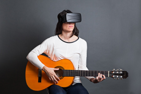 casual young woman learning how to play the guitar through virtual reality