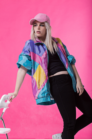 Stylish young woman posing against a pink background - studio shot