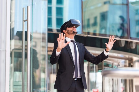 afro businessman playing virtual reality simulation, business buildings on the background