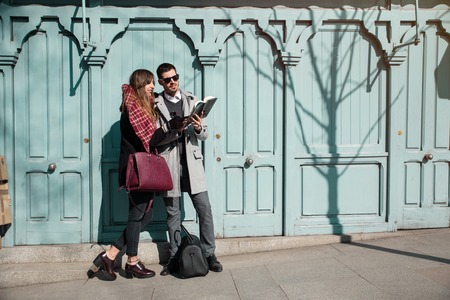 young fashionable couple looking at book in the streetの写真素材